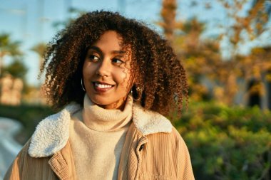 Genç Afrikalı Amerikalı kadın parkta mutlu bir şekilde gülümsüyor.