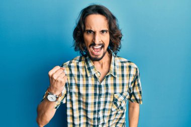 Latin asıllı genç bir adam, kızgın ve kızgın. Öfkeyle bağırırken yumruğunu sallıyor ve öfkeleniyor. öfke ve agresif konsept. 