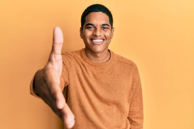 Genç, yakışıklı, sıradan bir süveter giyen, dostça gülümseyerek selamlaşan, hoş geldin diyen İspanyol bir adam. başarılı iş. 