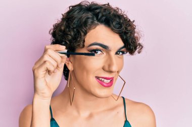 Kirpik rimel tutan genç bir adam pozitif ve mutlu görünüyor. Kendine güvenen bir gülümsemeyle dişlerini gösteriyor. 