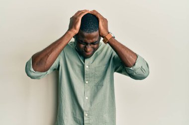 Genç Afro-Amerikan adam gündelik kıyafetler giyiyor. Baş ağrısı çekiyor, çaresiz ve stresli. Çünkü acı ve migren ağrısı var. Eller başının üstünde.. 