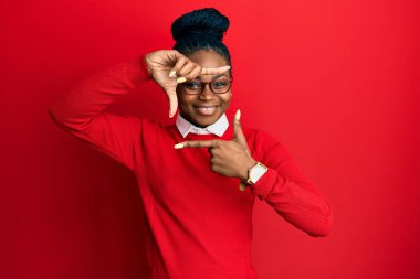 Gündelik kıyafetler ve gözlük takan, gülümseyen, elleri ve parmakları mutlu yüzlü genç Afro-Amerikan kadın. yaratıcılık ve fotoğrafçılık kavramı. 