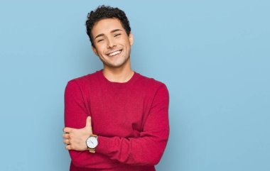 Sıradan kıyafetler giyen, kollarını kavuşturup kameraya bakan mutlu yüzlü genç bir adam. pozitif kişi. 