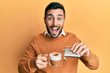 Genç İspanyol adam bir fincan kahveyi alkolle içiyor ve kahkahalarla gülüyor.. 