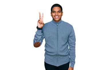 Genç, yakışıklı, sıradan bir kazak giyen, kendini beğenmiş, mutlu bir şekilde gülümseyen, iki numarayı işaret eden İspanyol bir adam.. 