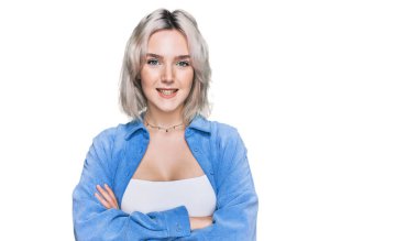 Sıradan kıyafetler giyen, kollarını kavuşturup kameraya bakan mutlu yüzlü genç sarışın kız. pozitif kişi. 