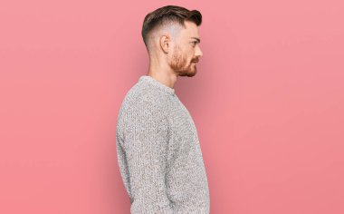 Kış süveteri giyen genç, rahat bir görünüm takınan, doğal yüzlü ve kendine güvenen bir gülümseme takınan genç bir adam.. 