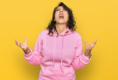 Latin kökenli genç bir kadın sıradan bir kazak giyiyor. Deli gibi bağırıyor, agresif bir ifadeyle bağırıyor ve kollarını kaldırıyor. hüsran kavramı. 