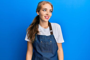 Güzel sarışın beyaz kadın temiz önlük ve eldiven giyer, rahat bir görünüm takınır, doğal bir yüz ve kendine güvenen bir gülümseme takınır.. 