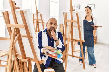 Sanat stüdyosundaki kıdemli sanatçı elleri çenesinde sorgulamayı, düşünceli ifadeyi düşünüyor. Gülümseyen ve düşünceli bir yüz. şüphe kavramı. 