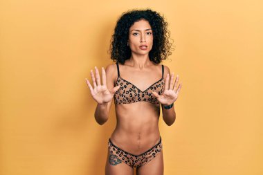Bikini giyen genç Latin kız avuç içlerini hareket ettiriyor. Korkmuş ve iğrenç bir ifadeyle reddediyor. Dur ve yasakla. 