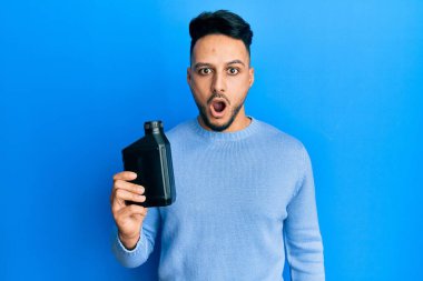 Motor yağı şişesi tutan genç Arap adam şaşırmak için ağzı açık kalmış, korkmuş ve hayrete düşmüştü. İnanmayan yüz. 