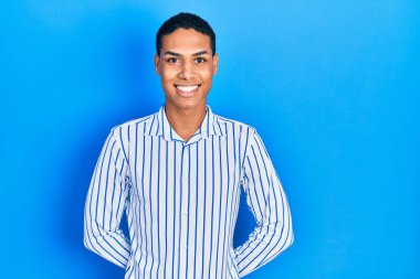 Yüzünde mutlu ve havalı bir gülümseme olan sıradan kıyafetler giyen genç bir Afrikalı Amerikalı. şanslı kişi. 