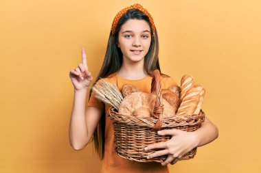 Genç esmer kız elinde hasırdan sepetle bir fikir ya da soruyla şaşırmış bir numaralı mutlu yüzü işaret ederek. 