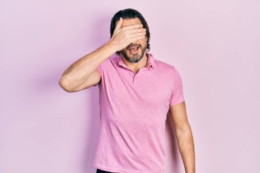 Orta yaşlı beyaz tişört giyen beyaz bir adam. Gülümsüyor ve elleri yüzünde, şaşırtmak için gözleri kapatıyordu. kör kavram. 