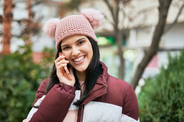 Genç İspanyol kız gülümsüyor. Şehirdeki akıllı telefondan konuşuyor..