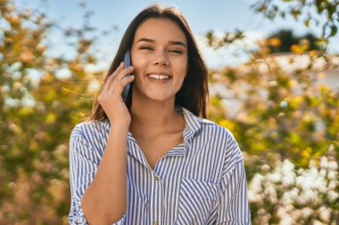 Genç İspanyol kız gülümsüyor. Şehirdeki akıllı telefondan konuşuyor..