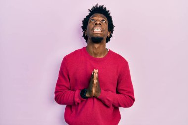 Genç Afro-Amerikalı bir adam günlük giysiler giyip elleri bağlı yalvarıyor ve dua ediyor. Yüzünde umut ifadesi var. Çok duygusal ve endişeli. Yalvarıyor. 