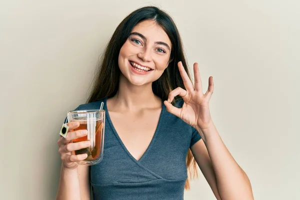 若い白人女性は指でOkサインを行うお茶のカップを保持します 笑顔優しいジェスチャー優れたシンボル — ストック写真