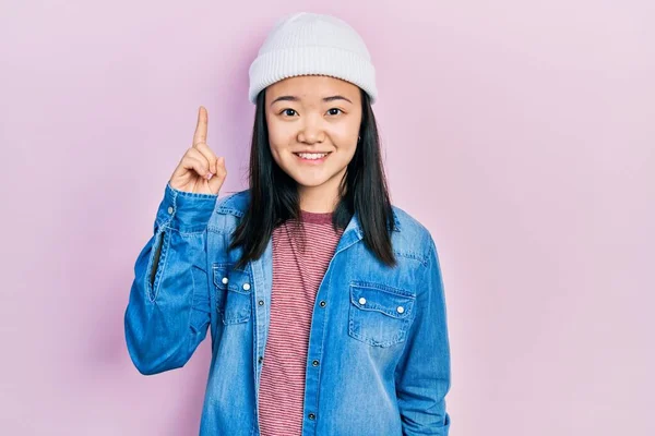 Young Chinese Girl Wearing Cute Wool Cap Pointing Finger Successful — Stock Photo, Image