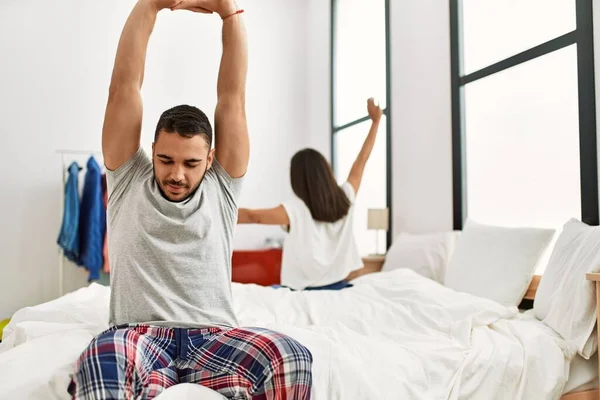 Jovem Casal Latino Bocejando Esticando Braços Sentados Cama — Fotografia de Stock