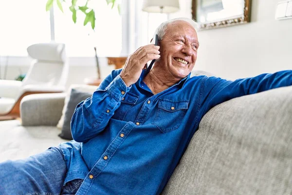 Starszy Mężczyzna Siwymi Włosami Siedzący Kanapie Salonie Rozmawiający Przez Telefon — Zdjęcie stockowe