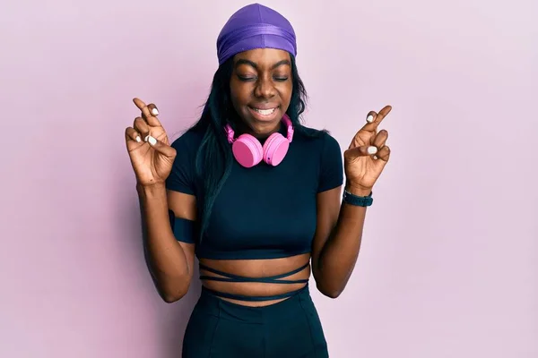 Młoda Afroamerykanka Ubrana Strój Gimnastyczny Używająca Słuchawek Trzymająca Kciuki Uśmiechnięta — Zdjęcie stockowe
