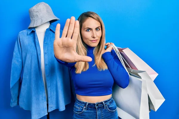 年轻的高加索女人张开手拿着购物袋 做了一个严肃而自信的停止手势 做了一个防御手势 — 图库照片