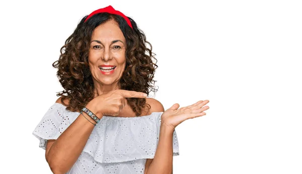 手で提示し 指で指差しながらカジュアルな服を身に着けている中年のヒスパニック女性は驚いてカメラに笑顔 — ストック写真