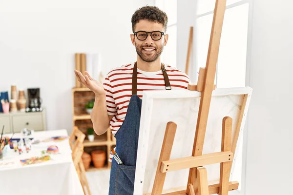 Arabský Mladý Muž Ateliéru Umění Vesele Usmívá Ukazuje Dlaní Ruky — Stock fotografie