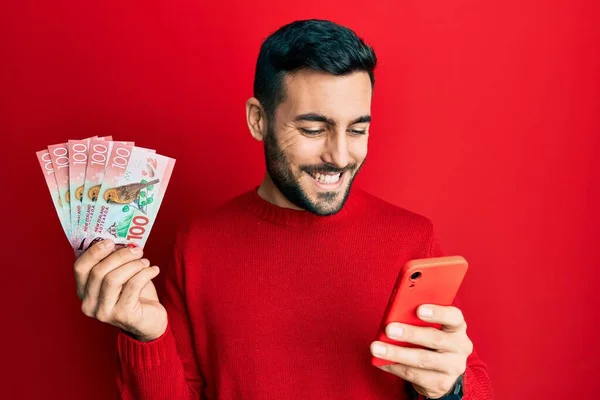 Fiatal Spanyol Férfi Okostelefont Használ Zélandi Dollárbankjegyekkel Mosolyogva Boldog Hűvös — Stock Fotó