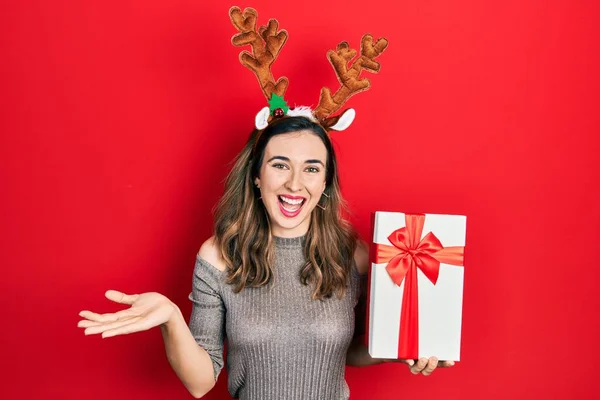 Joven Chica Hispana Con Sombrero Navidad Ciervo Sosteniendo Regalo Celebrando —  Fotos de Stock