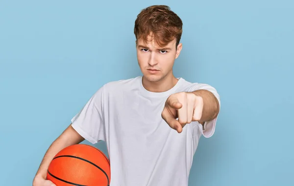 Pria Muda Kaukasia Memegang Bola Basket Menunjuk Dengan Jari Kamera — Stok Foto