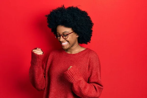 若いアフリカ系アメリカ人の女性がカジュアルな服と眼鏡を身に着けているのは驚きと腕を上げて目を閉じて成功に驚いて — ストック写真