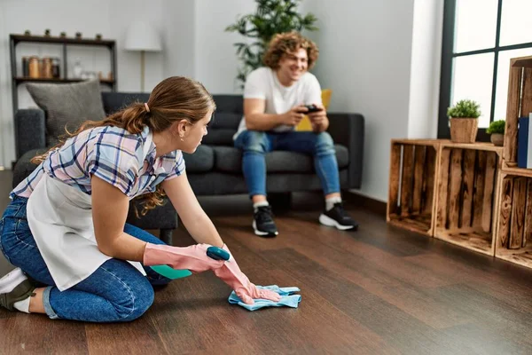 Kobieta Sprzątanie Domu Podczas Gdy Mężczyzna Gra Gry Wideo Domu — Zdjęcie stockowe