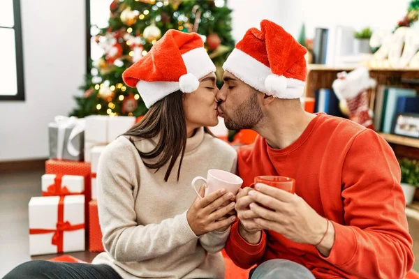 Young Hispanic Couple Kissing Drinking Cup Coffee Sitting Floor Christmas — Stock Photo, Image