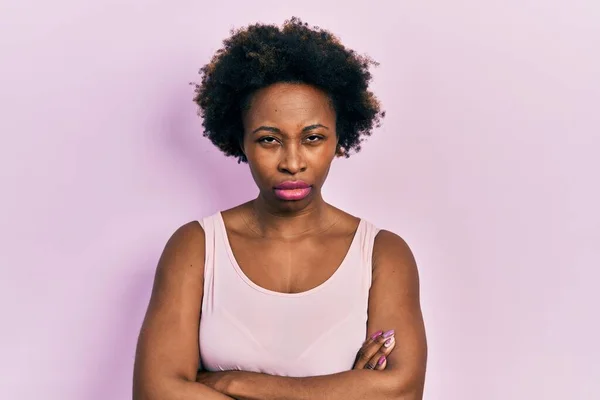 アフリカ系アメリカ人の若い女性は 平常のノースリーブのシャツを着て懐疑的で緊張し 両腕を組んで顔に不承認の表現をしています 否定的な人 — ストック写真