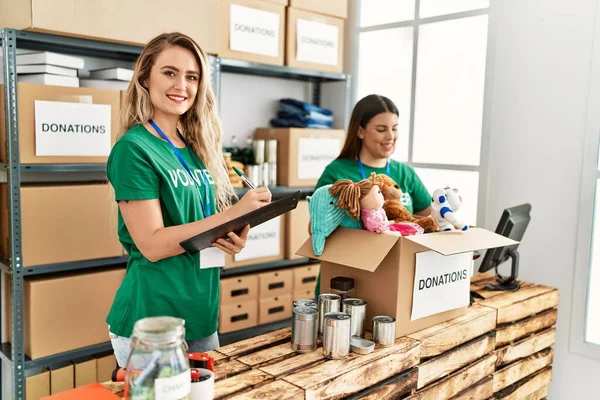 İki gönüllü kadın, hayır kurumunda çalışmaktan mutlu gülümsüyor..