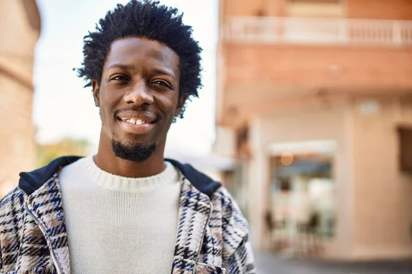 Handsome black man with afro hair and beard smiling happy outdoors