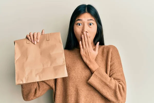 若い中国の女性は手で口をカバー紙の袋を奪う保持し ショックを受け ミスを恐れている 驚きの表情 — ストック写真