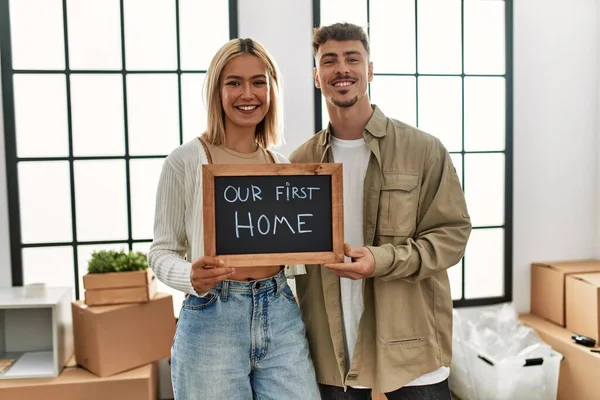 Young Caucasian Couple Smiling Happy Holding Blackboard Our First Home — Stock Photo, Image