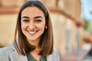 Genç İspanyol kız gülümseyerek şehirde mutlu mesut dikiliyor..