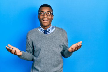 İş tarzı giyinmiş genç Afro-Amerikalı adam ve gözlük takan çılgın ve başarıyı kutlayan kollarını kaldırmış ve gözlerini kapatmış heyecanlı çığlıklar atan gözlüklü adam. Kazanan konsept 