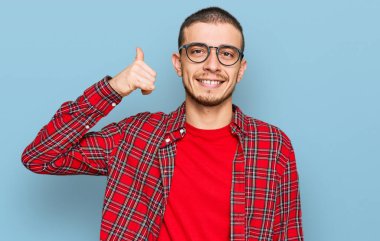 İspanyol genç adam günlük kıyafetler giyip gülümsüyor telefonla el ve parmaklarıyla jest yapıyor telefonda konuşuyor gibi. iletişim kavramları. 