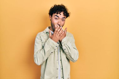 Gündelik kıyafetler giyen genç İspanyol adam yanlışlıkla elleri ile ağzını kapatırken şok oldu. gizli kavram. 