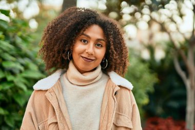 Genç Afrikalı Amerikalı kadın parkta mutlu bir şekilde gülümsüyor..