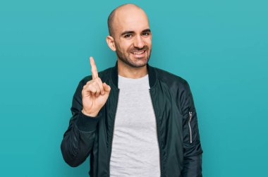 Gündelik kıyafetler giyen genç İspanyol bir numarayı gösterip işaret ederken kendinden emin ve mutlu bir şekilde gülümsüyor.. 