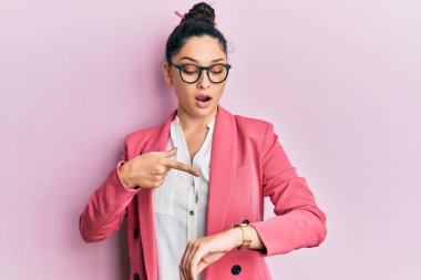 İş ceketi ve gözlük takan güzel ortadoğulu kadın saati, sabırsızlığı ve gecikmeye kızmayı işaret ediyor. 