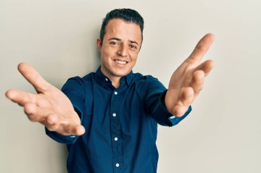 İş gömleği giyen yakışıklı genç adam kameraya sarılıp gülümseyerek gülümsüyor. Mutluluğu kucaklayan neşeli bir ifade.. 