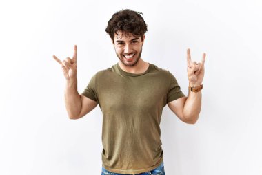 İspanyol adam izole edilmiş beyaz arka planda duruyor çılgın bir ifadeyle bağırıyor elleri havada rock sembolü yapıyor. Müzik yıldızı. ağır müzik konsepti. 